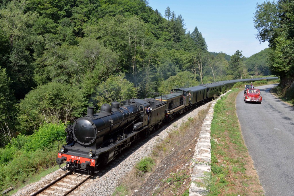 Le train à vapeur roule en parallèle d'une manifestation d'anciens véhicules en août 2015 entre St Léonard de Noblat et Châteauneuf-Bujaleuf. Photo : CFTLP